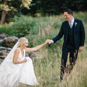 bride and groom at beaver creek wedding chapel, holding hands in tall grass, colorado wedding inspiration, mountain wedding planner, beaver creek weddings