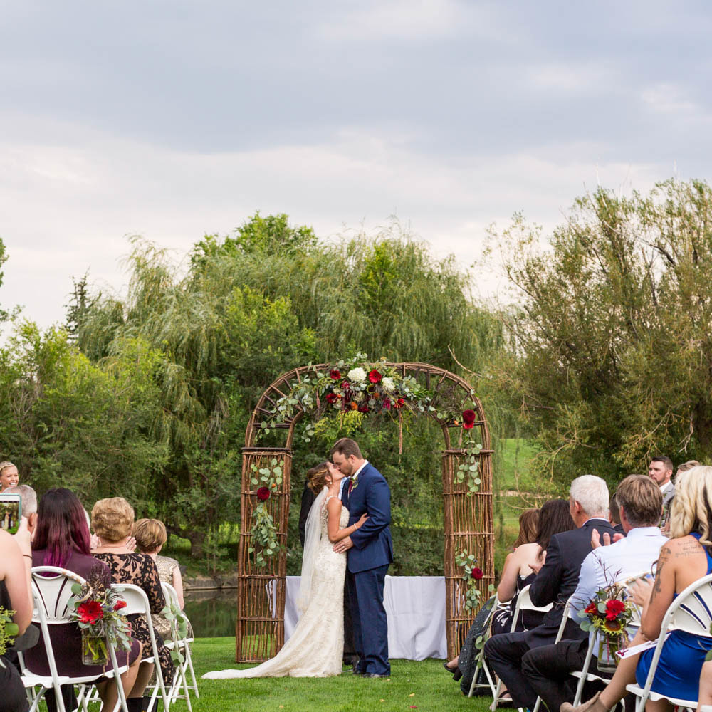 Ceremony twiggy arch with floral decor, first kiss, real weddings at lakewood country club, denver arch rental, colorado wedding inspiration, sweetly paired vail wedding planner, destination wedding planning