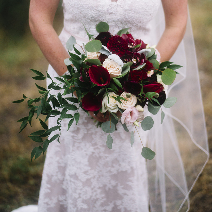 bridal bouquet, close up of bride holding bouquet, red and cream flowers, colorado wedding planner, mountain wedding inspiration, lace wedding dress, sweetly paired wedding planner