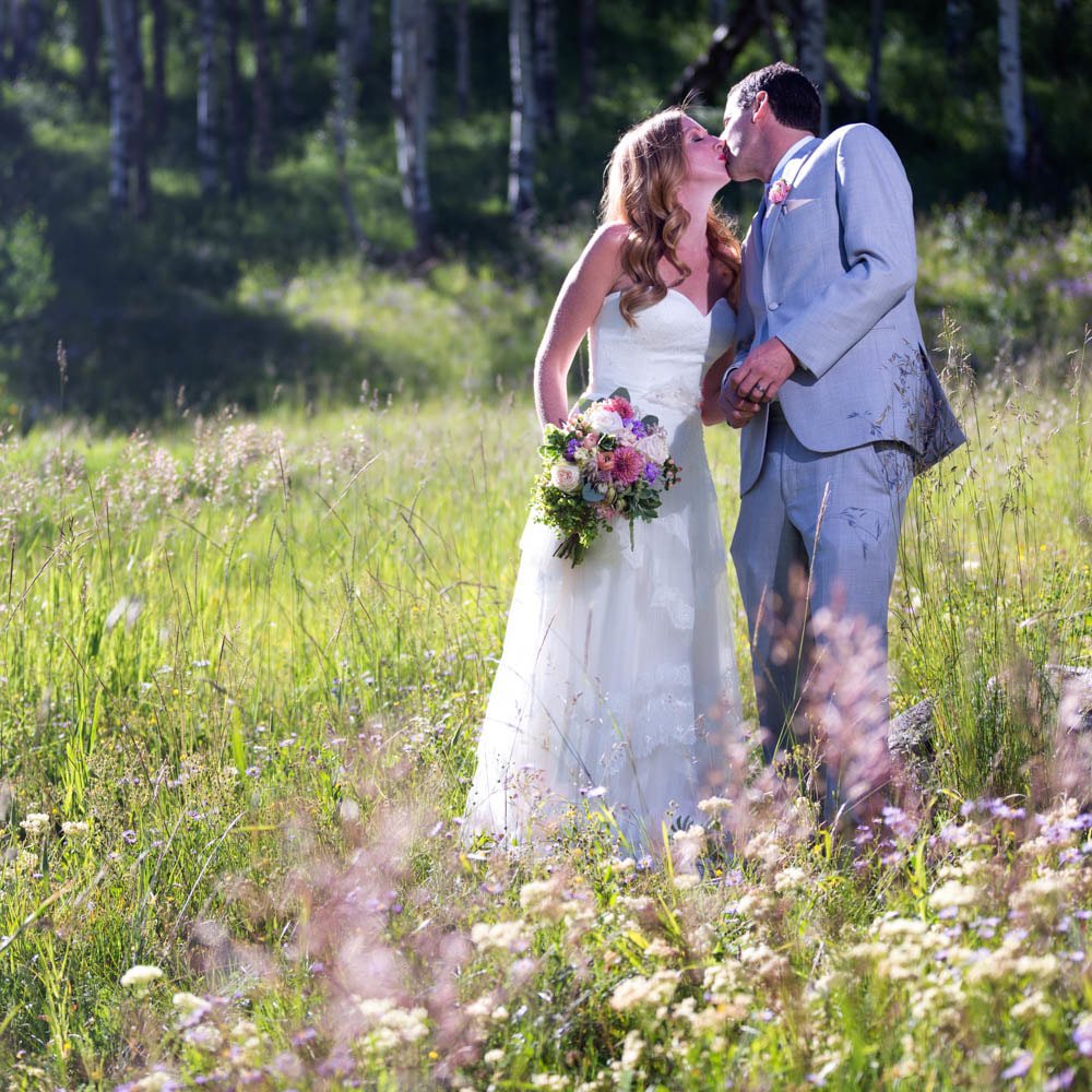bride and groom kissing in field at piney river ranch mountain wedding venue, colorado wedding inspiration, vail wedding planner, beaver creek wedding planner, sweetly paired weddings