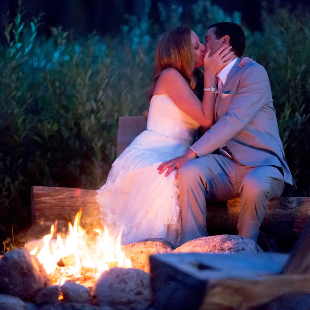 bride and groom kissing next to fire pit at night roasting smores, glamping wedding, piney river ranch wedding planner, mountain wedding inspiration, vail wedding planner, sweetly paired weddings