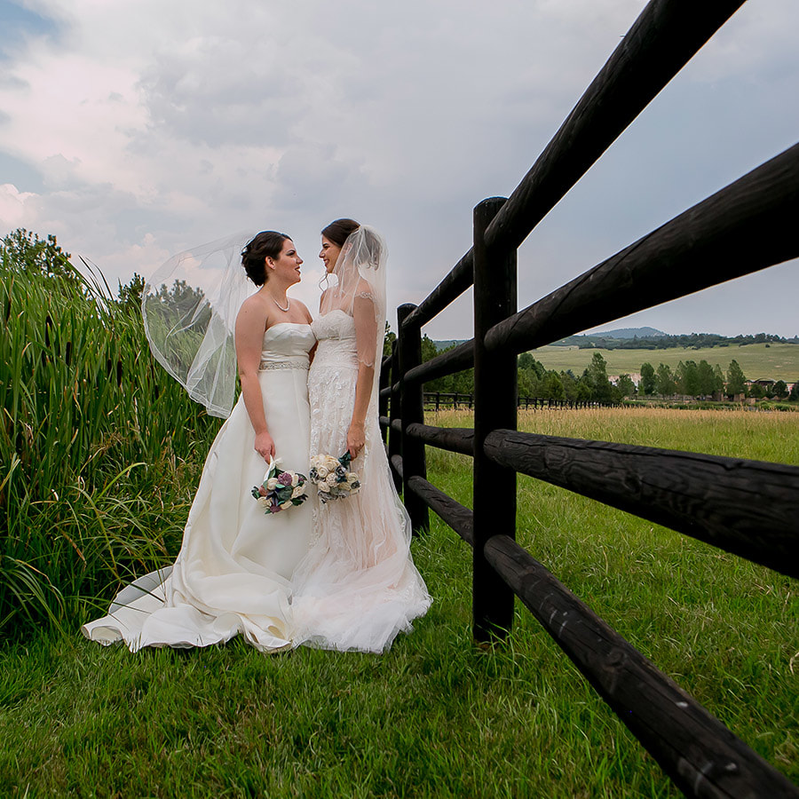bridal portraits, veil blowing in the wind, bride leaning against wooden fence, wooden bridal bouquets, lgbt wedding planning, sweetly paired wedding planner, spruce mountain ranch wedding planner, colorado wedding inspiration
