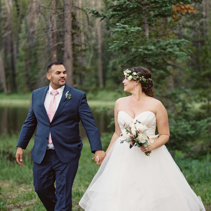 bride and groom holding hands walking through woods near lake at piney river ranch, colorado mountain weddings, vail wedding inspiration, sweetly paired wedding planners