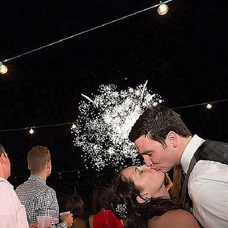 Outdoor wedding reception under market lights at willow ridge manor morrison colorado, denver wedding planner, sweetly paired weddings, bride and groom kissing under fireworks