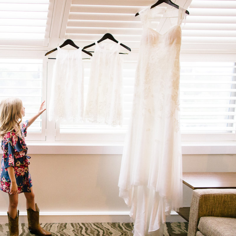 Bride getting ready photo, putting on dress, detail photos, denver wedding planner, colorado wedding planner, spruce mountain ranch alberts house, flower girl in floral robe looking at white dresses hanging in window