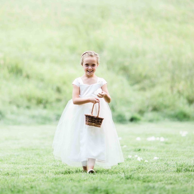 spruce mountain ranch ceremony, flower girl walking down the aisle with basket of petals, white dress, colorado mountain wedding, sweetly paired wedding planners, summer wedding inspiration