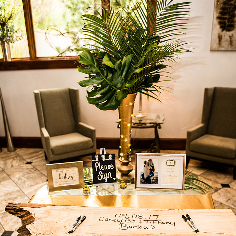 cielo at castle pines wedding planner, mountain wedding inspiration, colorado wedding planning, sweetly paired planners, gold and green wedding colors, palm fronds in gold vase, wooden board guest book, welcome table, reception details