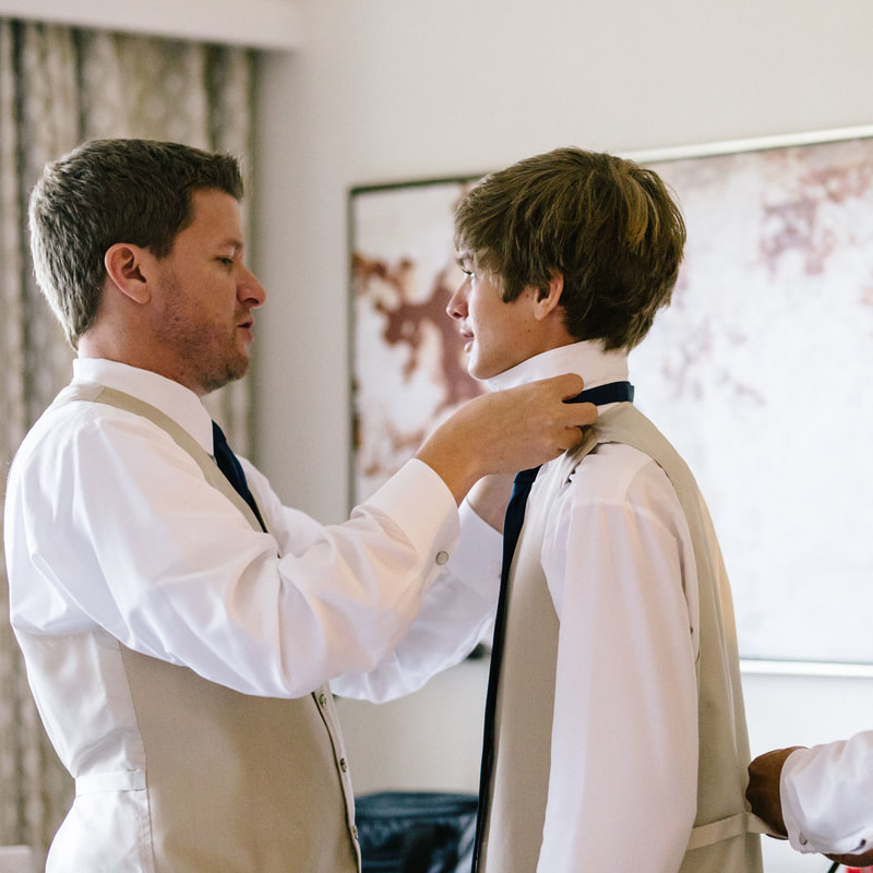 groom getting ready photo, putting tie on ring bearer, detail photos, denver wedding planner, colorado wedding planner, boutonniere, spruce mountain ranch