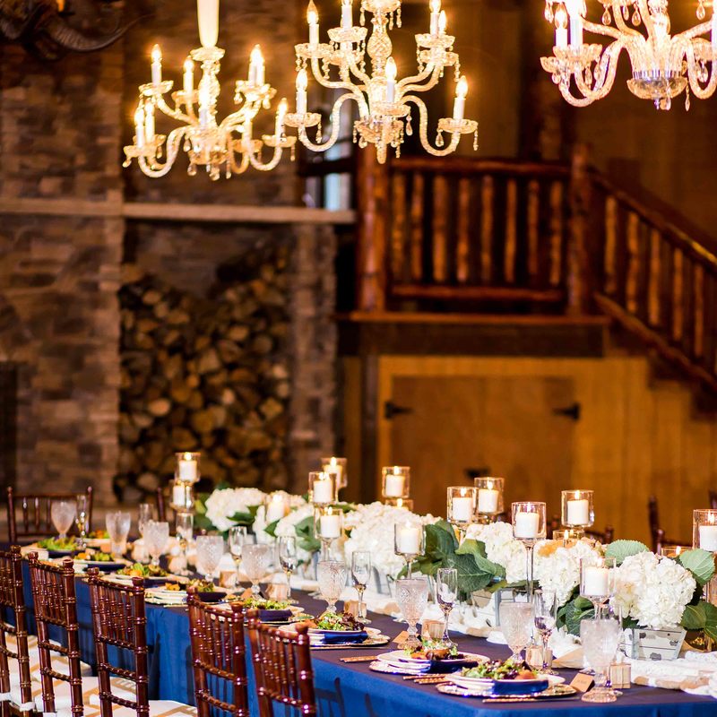 spruce mountain ranch head table, navy linens, kings table, chandeliers, white hydrangeas and candles, wooden chairs, rustic chic barn wedding, spruce mountain lower ranch, colorado wedding planner, mountain wedding planning