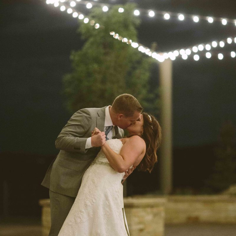 bride and groom portrait, kissing at night under the market lights outside at upper ranch, spruce mountain ranch wedding planners, colorado wedding inspiration, mountain wedding planner