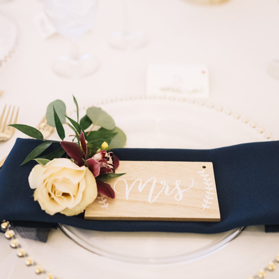 navy and gold wedding colors, table setting with wooden mrs sign and floral sprigs, cherokee ranch and castle wedding planner, colorado wedding planning, mountain wedding inspiration