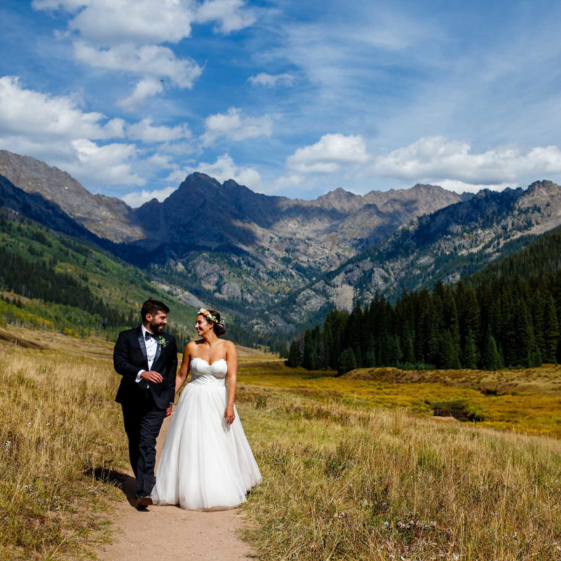 bride and groom holding hands walking along trail near lake at piney river ranch, colorado mountain weddings, vail wedding inspiration, sweetly paired wedding planners