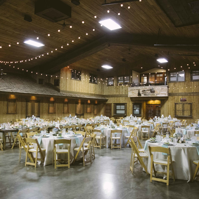 spruce mountain reception space, blue and white linens, kings table, market lights, blue hydrangeas and candles, wooden chairs, rustic chic barn wedding, spruce mountain upper ranch, colorado wedding planner, mountain wedding planning