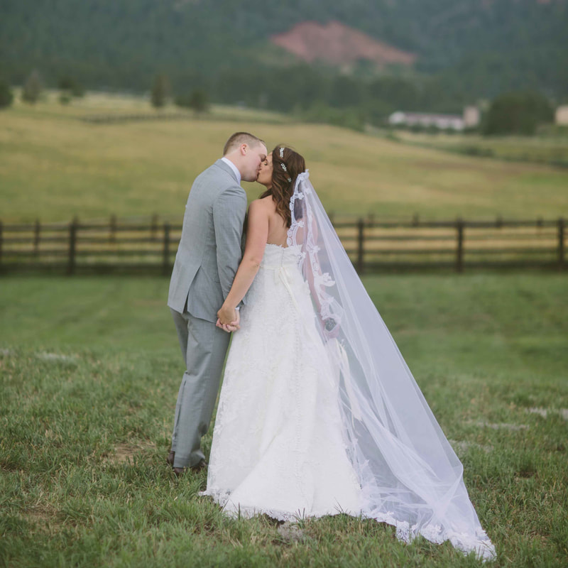 bride and groom portrait, kissing in field at spruce mountain ranch, mountain wedding planning, colorado wedding inspiration, sweetly paired